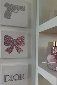 three canvases with bows on them are hanging on the wall next to perfume bottles