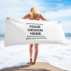 a woman standing on the beach holding a white towel that says, atlantic designs in black