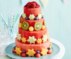 a three tiered fruit cake on a plate with strawberries and kiwis