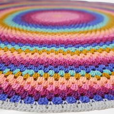 a multicolored crocheted blanket on top of a white table with a circular design