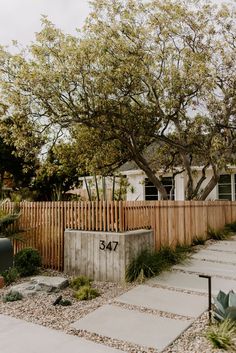 a wooden fence next to a tree in front of a house