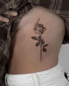 a woman's lower back with a rose tattoo on it