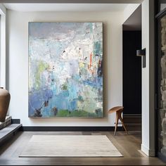 an abstract painting hangs on the wall next to a chair