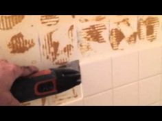 a man is using a drill to fix a bathroom wall with brown paint on it