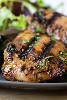 grilled chicken on a black plate with greens