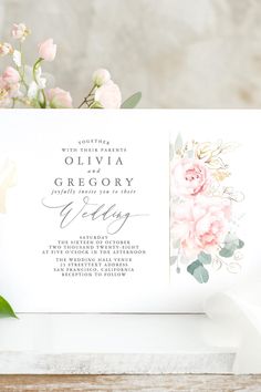 the wedding stationery is displayed with flowers and greenery