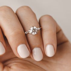 a woman's hand with a ring on it and a diamond in the middle