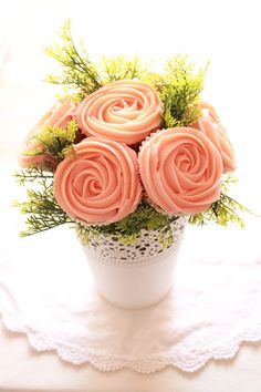 a white vase filled with pink roses on top of a doily next to a window