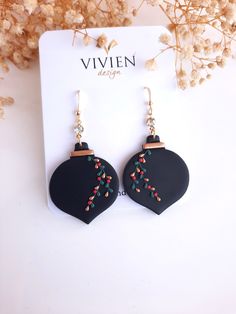 a pair of black heart shaped earrings with red and green beads