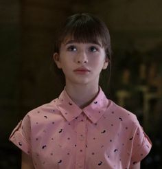 a young woman in a pink shirt looking at the camera