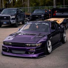 a purple car parked in a parking lot next to other cars