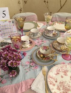 the table is set with pink roses and china