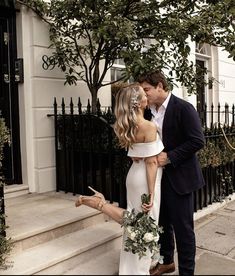 a bride and groom kissing on the street