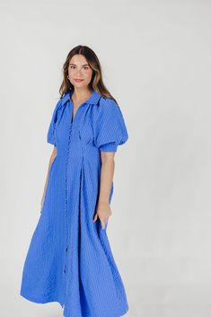 The Karsyn Midi Dress is a summertime must-have! This midi dress offers the comfortable shirt-dress silhouette we all love, but in an elevated design; its puffed short sleeves and darted bodice gives the Karsyn a flattering, feminine fit, while the beautiful textured fabric is lightweight and an eye-catching hue, perfect for all your summer jaunts. FIT: Runs true to size. MATERIAL: Shell: 100% Polyester; Lining: 100% Cotton. Hand wash cold; not not bleach, do not tumble dry. Iron low. GARMENT DE Blue Puff Sleeve Dress With Short Sleeves For Summer, Blue Puff Sleeve Dress For Summer, Relaxed Fit Short Sleeve Midi Dress For Daywear, Summer Puff Sleeve Maxi Dress For Day Out, Chic Short Sleeve Midi Dress For Daywear, Summer Puff Sleeve Dress With Gathered Sleeves, Puff Sleeve Short Sleeve Summer Dress, Summer Workwear Dresses With Puff Sleeves, Spring Short Sleeve Shirt Dress For Day Out