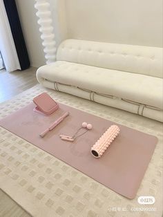 a living room with a white couch, pink rug and various items on the floor