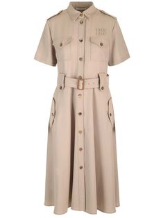 Midi dress in light brown wool gabardine from Miu Miu, with buttons along the entire length, short sleeves, chest and side pockets with flap, flared midi skirt. Luxury Miu Miu Skirt For Workwear, Classic Workwear Dresses With Buttoned Pockets, Beige Short Sleeve Midi Dress For Work, Short Sleeve Midi Dress With Pockets For Work, Short Sleeve Midi Dress With Button Cuffs For Work, Workwear Midi-length Shirt Dress With Buttoned Pockets, Midi-length Shirt Dress With Buttoned Pockets For Work, Beige Short Sleeve Dress For Work, Beige Belted Short Sleeve Shirt Dress