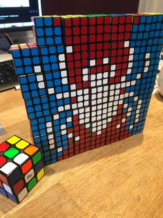 a rubik cube sitting on top of a wooden table next to a computer monitor