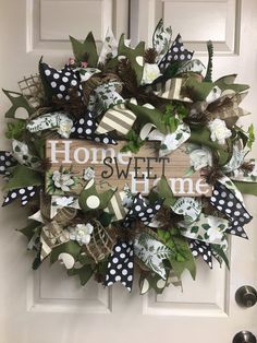 a wreath that says home sweet and decorated with black and white polka dots, green leaves and flowers