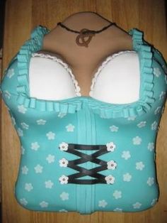 a cake shaped like a bra with flowers and laces on the front, sitting on top of a wooden table