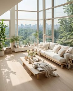 a living room filled with lots of windows and furniture next to a large window covered in greenery