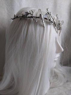 As serene as the silver moon, this tiara captures the essence of the glistening night sky as the moonlight paints the forest below a stunning silver, illuminating the landscape with an icy glow. This tiara features silver leaves surrounding the piece, a crescent moon, silver branches, and five silver titanium colored quartz (or clear quartz if you choose). This tiara is a unique and gorgeous handmade piece that will make a great gift. Adjustable Silver Wedding Crown, Silver Adjustable Crown With Pinched Shape, Adjustable Silver Crown For Parties, Adjustable Silver Crown For Party, Silver Structured Crown For Party, Silver Headband Crown For Wedding, Silver Fantasy Wedding Headpiece, Silver Tall Crown Headpiece For Party, Silver Fantasy Party Headpiece