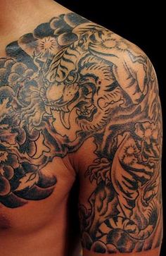 a man with tattoos on his chest and shoulder is looking at the camera while he's showing off his tiger tattoo