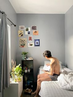 a man sitting on top of a bed next to a window