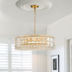 a chandelier hanging from the ceiling in a room with white walls and windows