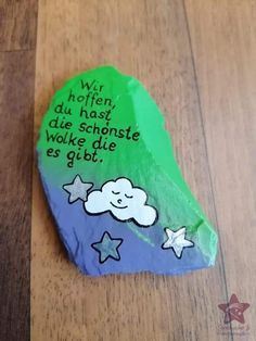 a rock with writing on it sitting on top of a wooden floor covered in green paper