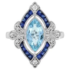 an aqua and white topazte ring with blue sapphires in the center, surrounded by diamonds