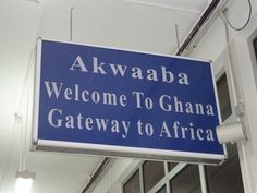 a blue sign hanging from the side of a building that says, akwaba welcome to ghana gateway to africa