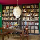 a dining room with green walls and lots of bookshelves