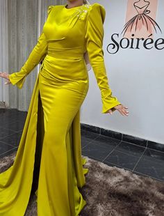 a woman in a long yellow dress posing for the camera with her hands on her hips