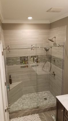 a walk in shower sitting next to a white sink and counter top under a faucet