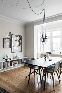 a dining room table and chairs in front of a window with pictures on the wall