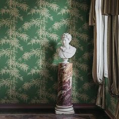 a marble busturine stands in front of a green wallpapered room with bamboo trees