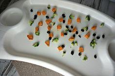 a white tray with carrots, broccoli and black olives on it