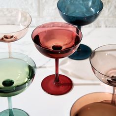 several different colored glasses sitting on top of a white countertop next to each other