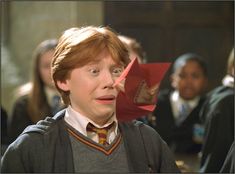 the young harry potter is holding an origami boat in his hand and looking surprised