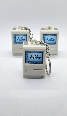 two keychains that have been made to look like an old computer monitor with the word hello written on it