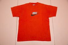 "Vintage NIKE 90's orange essential Nike Swoosh graphics t-shirt. Made in Turkey. It is pre-used and in very good vintage condition. Size on label: M as medium. Please compare your measurements with the measurements provided below before buying this item. Length from center back: 65 cm / 25.59\" inches Chest: 54 cm / 21.26\" inches Sleeve Length, from arm opening: 21 cm / 8.27\" inches Shoulder to shoulder: 44 cm / 17.32\" inches Material: 100% cotton. Condition: very good vintage used condition T Shirt Nike Orange, 90s Style Red T-shirt For Sports, Orange Graphic T-shirt For Streetwear, Orange Graphic Design T-shirt For Streetwear, Sporty Orange T-shirt With Letter Print, Red 90s Style Sports T-shirt, 90s Red T-shirt For Sports, Orange Sports T-shirt With Letter Print, Orange Letter Print Sports T-shirt