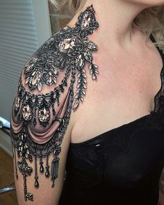 a woman's shoulder with black and white tattoos on her arm, which is covered in lace