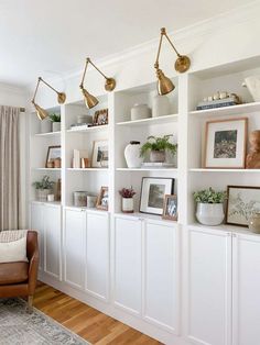 a living room filled with lots of white bookshelves covered in pictures and plants