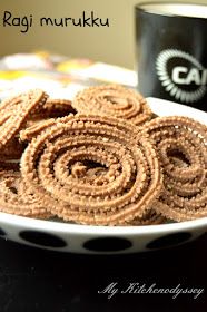 some food on a white plate next to a black and white coffee cup with the words ragi murukku