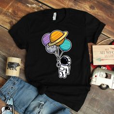 a black shirt with an astronaut holding balloons