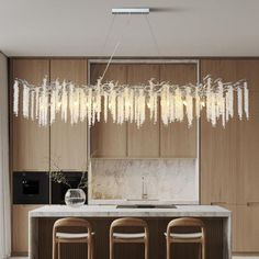 a kitchen with wooden cabinets and white marble counter tops, hanging chandelier over the island