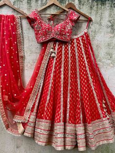 A three-piece red bridal sharmily embroidered lehenga set from the Priti Sahni collection. This beautiful and graceful georgette red butti bridal panel lehenga with a heavy border of gota, pearl, sequin, zari detail is paired with a red raw silk blouse with zardozi, sequin, & hand-embroidery work. The zari panelled lehenga has side hanging ball tassels to the waistline. And the blouse has a sequin-bead tassel tie-up at the back. This outfit is completed with a red tulle sequin butti dupatta with Red Georgette Sharara With Cutdana, Red Cutdana Lehenga For Reception, Red Georgette Lehenga With Cutdana, Red Georgette Choli With Cutdana, Red Georgette Sharara With Dori Work, Red Floor-length Lehenga With Cutdana, Red Georgette Sharara For Reception, Red Georgette Lehenga For Navratri, Red Georgette Sets With Dupatta