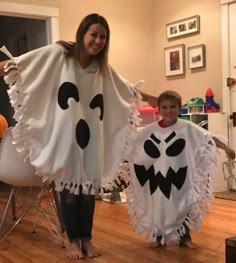 a woman standing next to a little boy in a room with halloween decorations on the walls