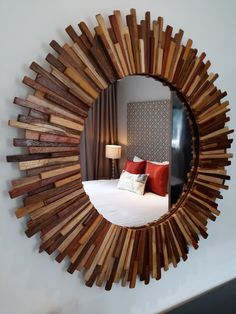 a mirror that is on the wall in front of a bed with pillows and throw pillows