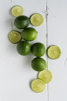 limes and lime slices on a white surface